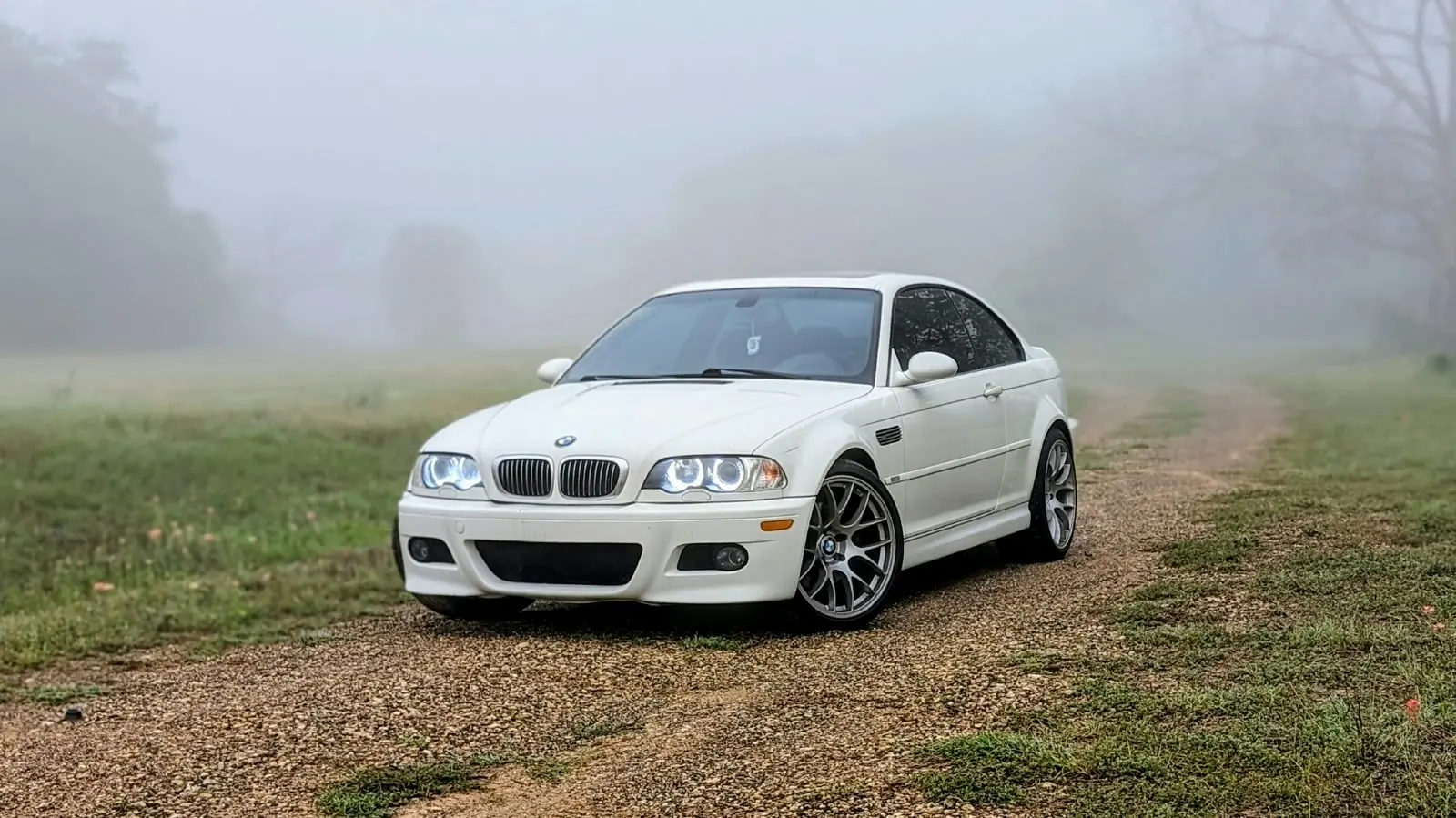 White BMW M3 parked on a foggy rural road